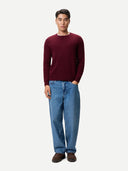 Man wearing a burgundy sweater and blue jeans on a white background #color_zinfandel