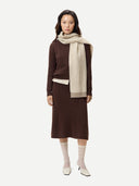 Woman wearing a brown dress, beige scarf, and white socks on a white background. #color_deep-mahogany