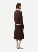 back view of a woman wearing a brown dress, beige scarf, and white socks on a white background. #color_deep-mahogany
