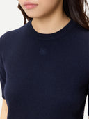 close up of a woman wearing a dark navy sweater with a small brand logo at the top center on a white background #color_navy-blazer