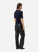 back view of a woman wearing a navy blue short-sleeve cashmere top and black leather pants on a white background #color_navy-blazer