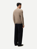 back view of a man wearing a beige checkered sweater and black pants on a white background #color_taupe
