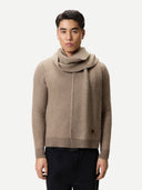 Man wearing a beige sweater with a high collar on a white background.