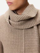 Close-up of a person wearing a beige textured sweater with a high collar.