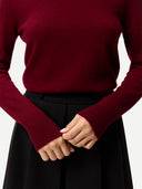 Close up of  a maroon sweater worn by a person on a white background #color_bordeaux