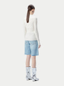 back view of a person wearing a white sweater, light blue shorts, and silver boots on a white background #color_whisper-white