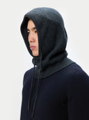 Person wearing a dark gray hooded hat and navy sweater against a light gray background #color_charcoal