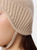 Close-up of a person wearing a beige knitted headband. #color_beige