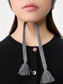 Person wearing a black sweater with gray knit ear covers and tassels. #color_dim-gray