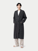 Person wearing a dark gray robe over a white shirt on a white background