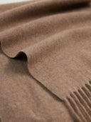 Close-up of a brown blanket with fringed edge.
