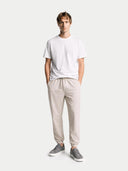Man wearing a white t-shirt and beige jogger pants on a white background #color_stone-gray
