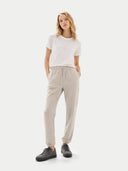 Woman wearing a white t-shirt and beige jogger pants on a white background #color_frost-gray
