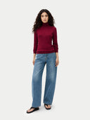 front view of a woman wearing a burgundy turtleneck sweater and blue jeans on a white background #color_bordeaux