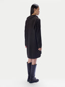 A model shown from the back wearing a dark brown long-sleeved hooded tunic dress and dark navy knee-high boots, set against a plain light gray studio background.