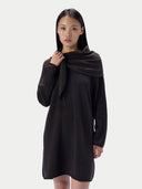 A model wearing a dark brown, long-sleeved knit dress with a draped, shawl-like collar, photographed against a solid light gray background.