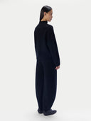 Black sleeveless top with a draped design worn by a model on a white background