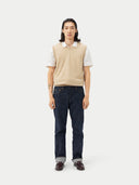 front view of man wearing a beige v-neck vest over a white polo shirt and jeans  #color_beige