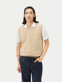 man wearing a beige v-neck vest over white polo shirt and jeans  #color_beige