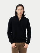 A man wearing a black half-zip cashmere sweater with long sleeves, standing against a plain background. #color_black