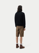 back view of a black half zip cardigan and brown shorts standing against a plain background. #color_black