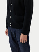 close up of a black cardigan with side pockets and blue jeans  #color_black
