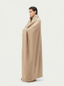 Side view of a person wrapped in a beige blanket on a white background #color_beige