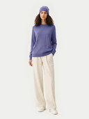 Woman wearing a purple sweater and white pants on a white background #color_dusted-peri