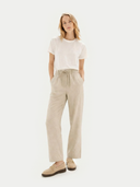 Woman wearing a white t-shirt and beige pants on a white background #color_warm-grey