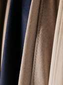 Folded cashmere sweaters in grey, olive and oatmeal on a mossy rock in autumn woodland