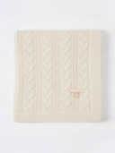 Cream-colored cable knit blanket with a button on a white background