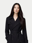 Woman wearing a black trench coat against a white background #color_black