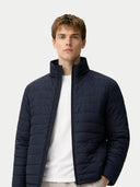 front view of man wearing a navy blue puffer jacket on a light gray background #color_navy-blazer