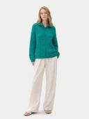 front view of a woman wearing a teal sweater and white pants on a white background #color_dynasty-green