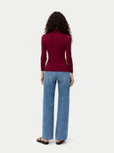 back view of a woman wearing a burgundy long-sleeve top and light blue jeans on a white background #color_bordeaux