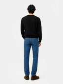 back view of a man wearing a black sweater and blue jeans on a white background #color_black