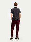 back view of a man wearing a dark gray polo shirt and maroon pants on a white background #color_charcoal