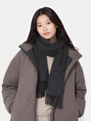 Woman wearing a gray coat and dark gray scarf on a white background