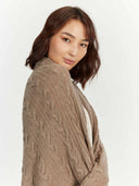 close up of a beige cable knit blanket wrapped by woman #color_taupe