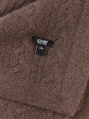 Close-up of a brown GOBI cable-knit 100% Mongolian cashmere scarf showing the brand tag "GOBI".