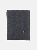 Charcoal grey cable-knit blanket with a branded label, folded on a white background. #color_charcoal