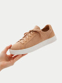 Beige sneaker with white sole held by a hand on a light gray background #color_toasted-almond