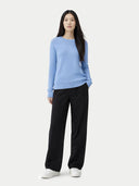 Woman wearing a light blue sweater and black pants on a white background #color_della-robbia-blue