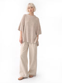 Woman wearing a beige poncho and wide-leg pants on a white background #color_biscotti