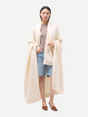 Model draped in white cashmere blanket with twill weave, front view, full length