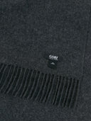 a zoomed-in shot of a dark gray fringed cashmere blanket with a black brand label "GOBI" #color_charcoal