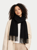 Woman wearing a black scarf with fringes on a plain background #color_black