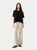 Woman wearing a black top and beige pants on a white background #color_black