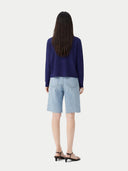 back view of Woman wearing a blue top and light blue shorts on a white background #color_navy