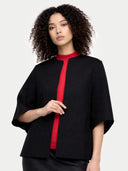 Woman wearing a black poncho jacket with a red top on a white background #color_charcoal